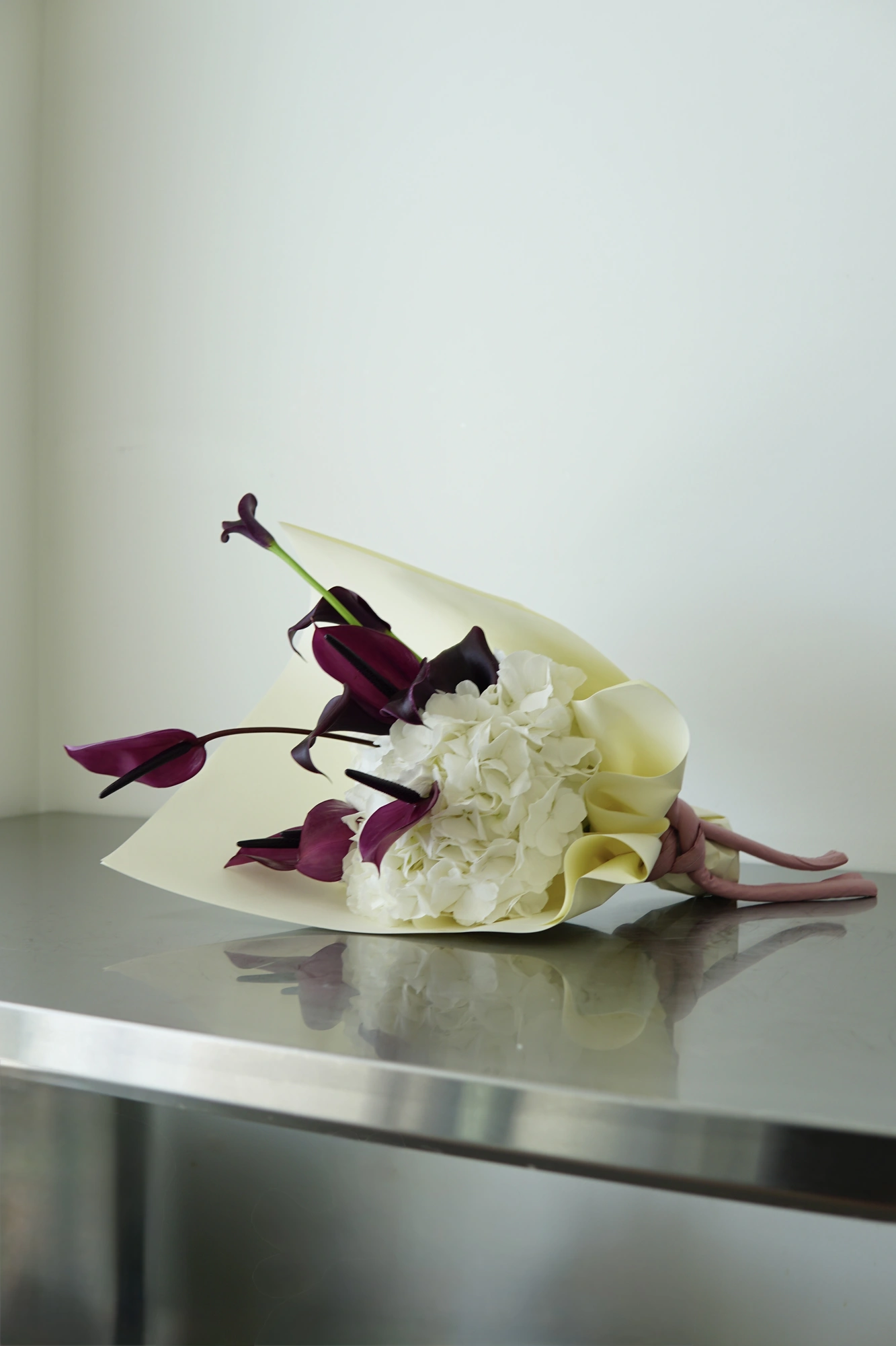 White hydrangea and dark calla lilies resting on a steel table