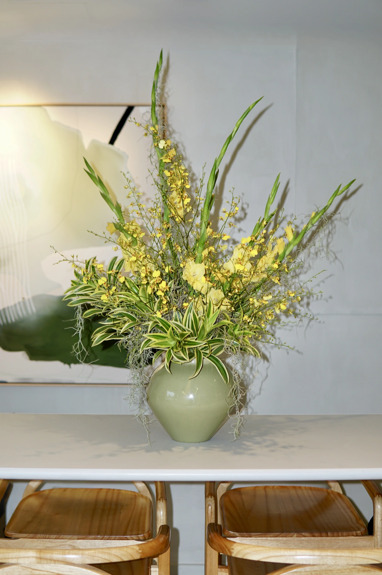 Yellow dancing-lady orchids and gladiolus in a sage vase