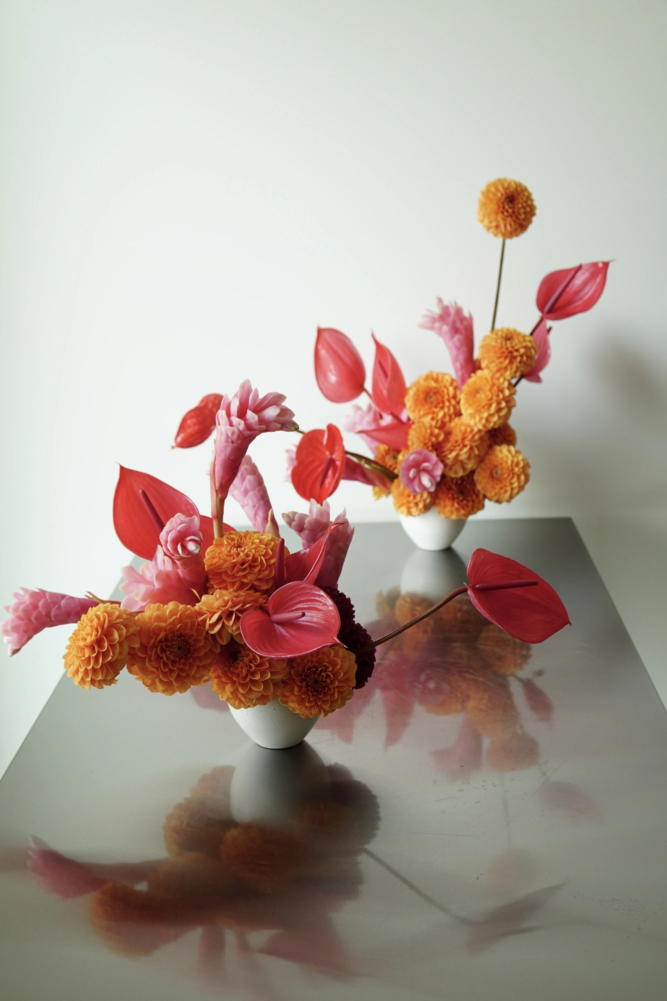 Two birthday arrangements of orange dahlias, red anthurium, and pink ginger