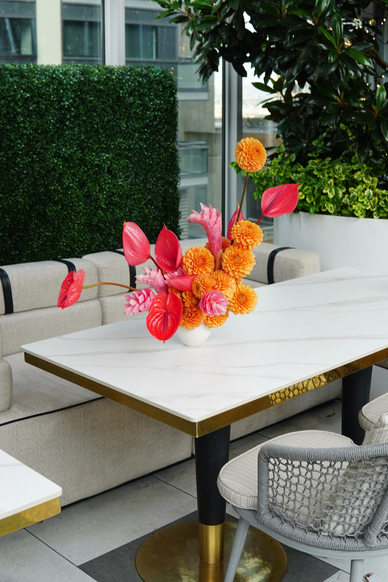 Orange dahlia and red anthurium arrangement on a marble table at Lavantine Restaurant
