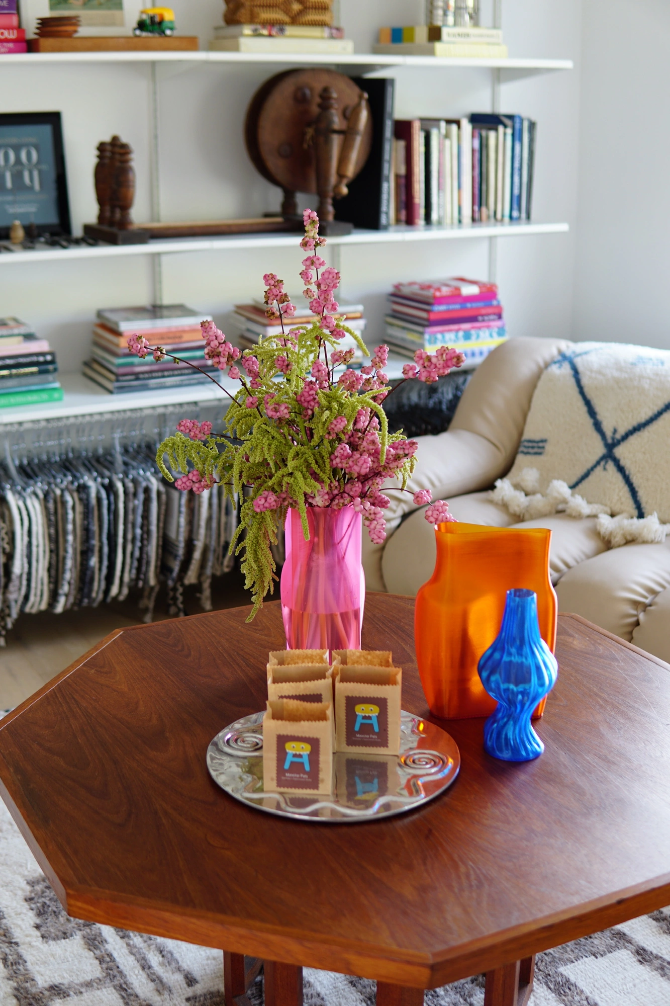 Pink amaranthus in a translucent pink vase beside orange and cobalt vessels