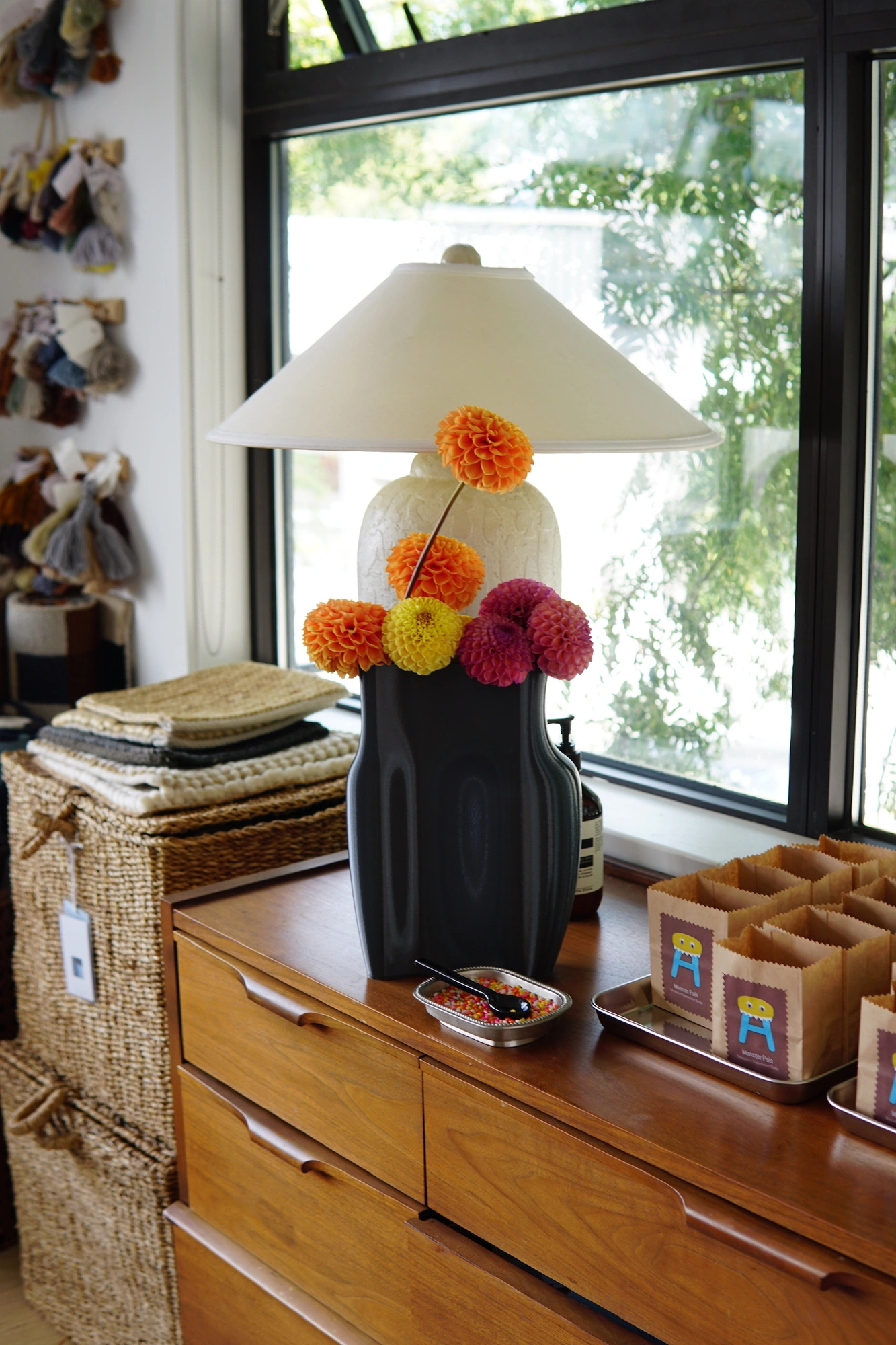Dahlias in orange, yellow, and magenta arranged in a dark sculptural vase