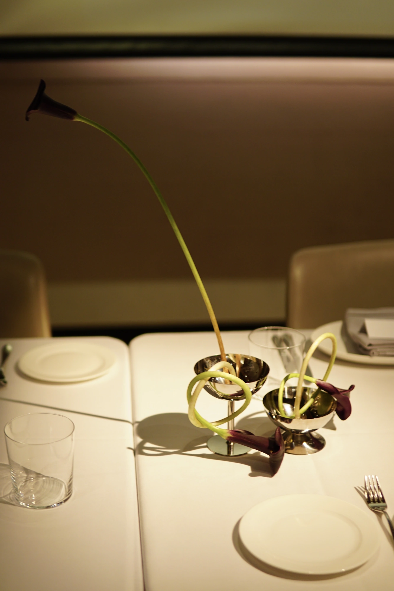 Single arching calla lily in a steel cup between place settings